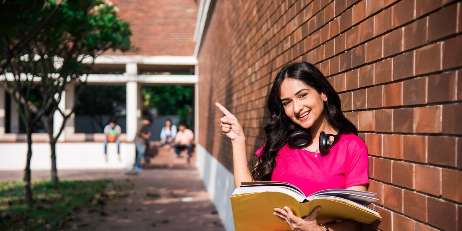 An Asian Indian college student focused on a laptop or book, with classmates in the background on a university campus—representing learning at a Digital Marketing Institute in Surat.